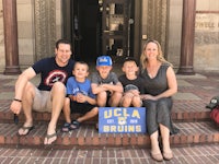 a family sits on the steps of a building with a sign that says ucla