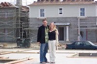 a man and a woman standing in front of a house under construction